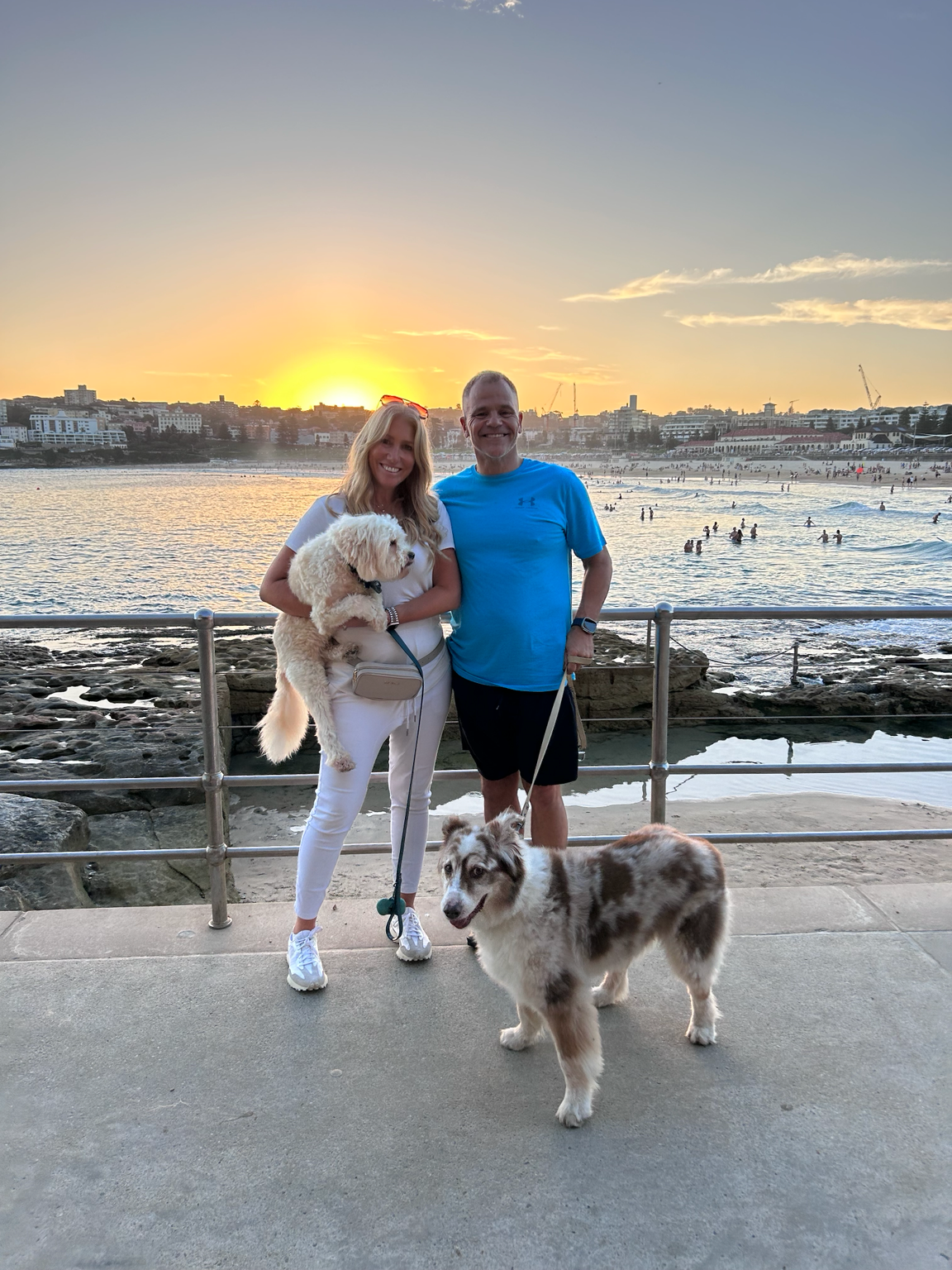 Paul and Lara with their dogs beside the ocean at sunset.