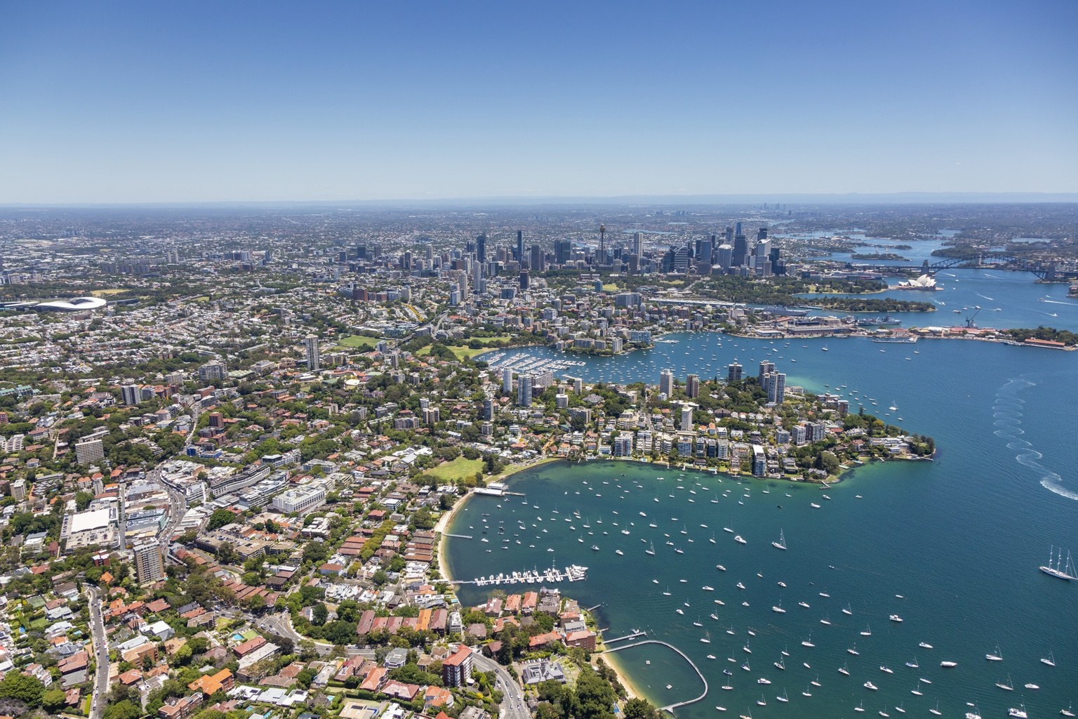 A wide aerial view across Sydney Harbour, its neighbourhoods and the city skyline